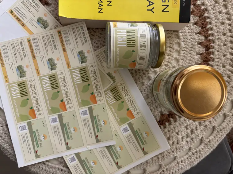 Printed sheets of Malayali Kada product stickers on a table